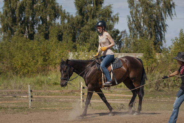 Уроки верховой езды - молодая женщина верхом на лошади
