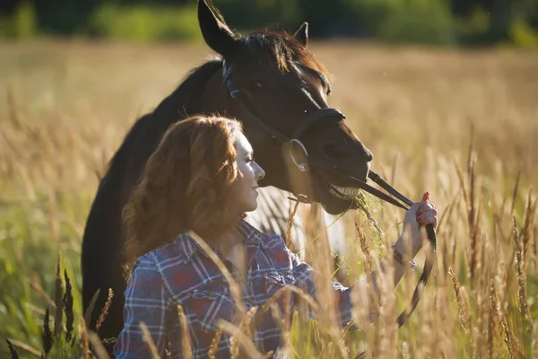 Ung kvinna gå med hästen i ängen vid sommardag — Stockfoto