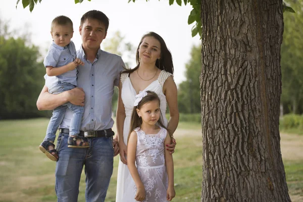 Gezonde familie in een park op zomeravond - vader, mammy, dochter en kleine jongen — Stockfoto