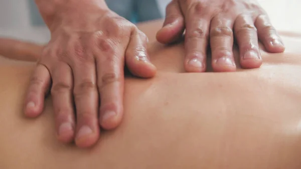 Spa. Massagem para mulher loira modelo - mão de homem em meninas de volta - close-up — Fotografia de Stock