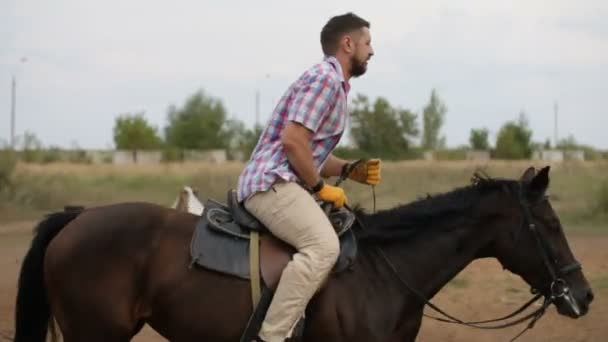 El hombre barbudo está montando a caballo - lección de equitación en el hipódromo, cámara lenta — Vídeo de stock