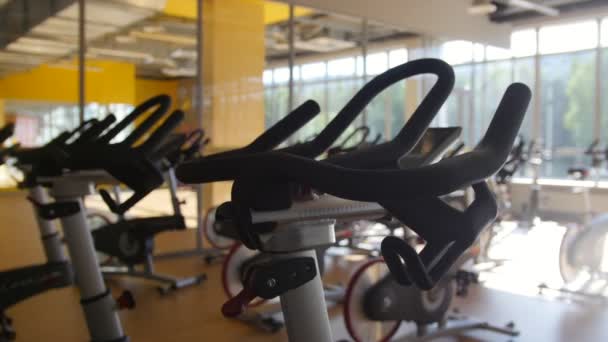 Simuladores de ciclismo no ginásio, interior do clube de fitness moderno, tiro deslizante — Vídeo de Stock