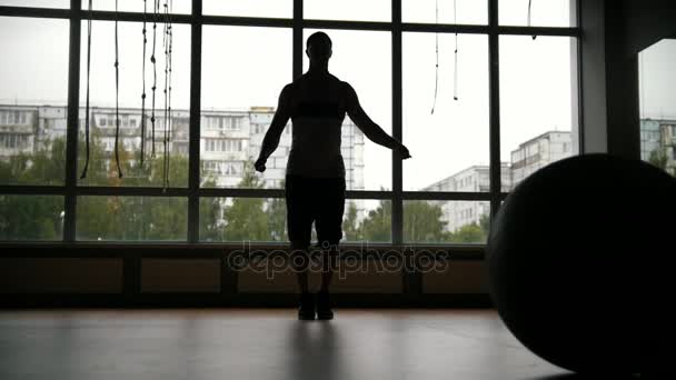 Hombre musculoso haciendo ejercicios de salto de cuerda en el gimnasio - silueta, cámara lenta — Vídeos de Stock