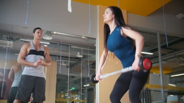 Девушка с тренером в спортзале поднимает штангу, замедленная съемка — стоковое видео