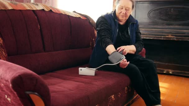 Пенсионер - старшая леди проверяет свое состояние здоровья с помощью манометра - измеряет давление, закрыть — стоковое видео