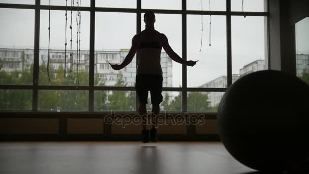 Muskularny mężczyzna robi liny skok poćwiczyć w siłowni - sylwetka, zwolnionym tempie - suwak strzał — Wideo stockowe
