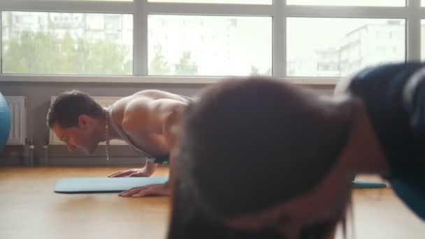 Pareja deportiva - chica y hombre haciendo flexiones juntos en el gimnasio - culturismo para la familia — Vídeos de Stock