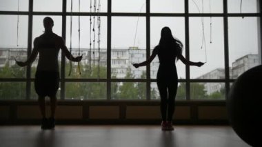 Fitness salonunda - sportif kadın ve ipi penceresinde yakınındaki kaslı adam atlar siluet