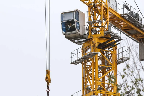 Construction crane - yellow metal tower and white cabin - close up