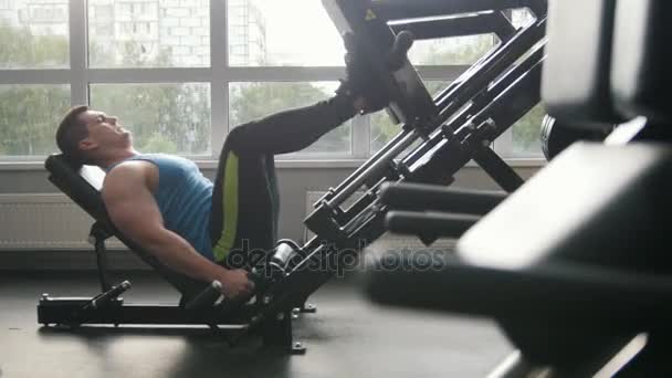 В тренажерном зале - мускулистый мужчина тренируется на машине для пресса ног — стоковое видео
