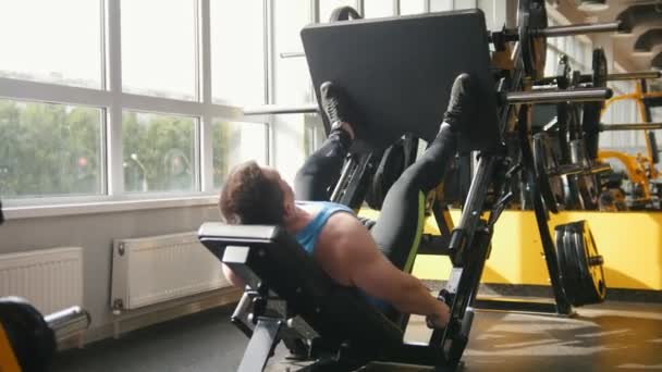Фитнес-клуб - мускулистый человек, тренирующийся на прессе для ног — стоковое видео