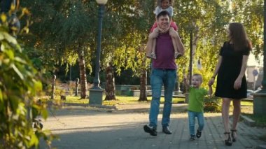 Sağlıklı aile baba, anne, kızı ve küçük çocuk, yavaş hareket yaz akşamları - parkta yürüyüş