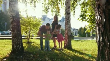 Aile yaz Park'ta yürüyordunuz günbatımında-baba, anne ve çocuk