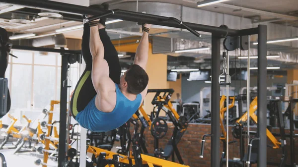 Genç atlet spor salonunda pull-up bar karın egzersiz yaparak adam