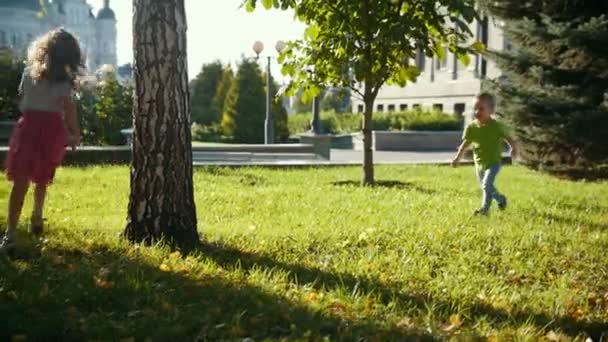 Çocuk - kız ve erkek - yaz parkta oynarken günbatımında - küçük erkek ve kız, ağır çekim — Stok video