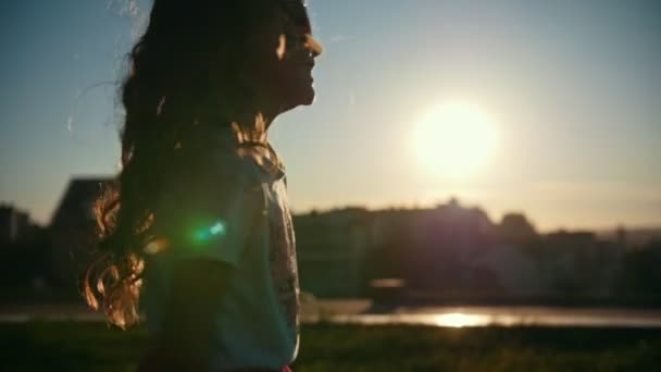 Маленька біла дівчинка грає і танцює на свіжому повітрі під час заходу сонця, повільний рух — стокове відео