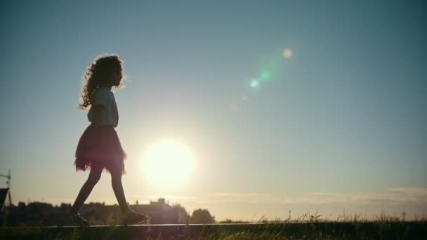 Liten flicka som leker och promenerar i parken, siluett på solnedgången, slow motion — Stockvideo