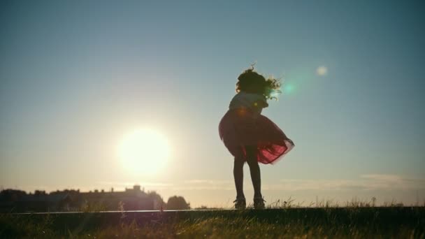 Девочка играет и прыгает на закате - дочь падает, замедленная съемка — стоковое видео