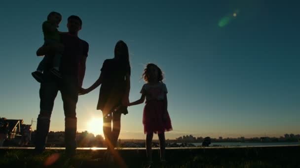 Porträt einer ganzen Familie - Vater, Mutter, Tochter und kleiner Sohn - Silhouette bei Sonnenuntergang vor der Skyline — Stockvideo