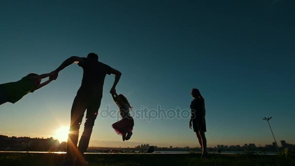 Šťastná rodina v západu slunce silueta - otec hraje s dětmi, pomalý pohyb — Stock video