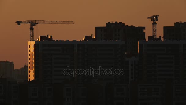 Byggkranar nära bostadslägenheter - Visa på sunrise — Stockvideo