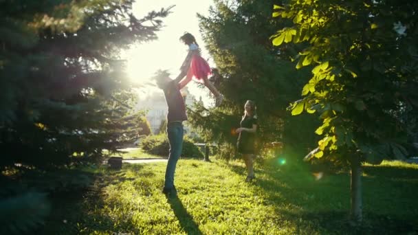 Lycklig familj i park - far kastar dotter i solnedgången - slow motion — Stockvideo