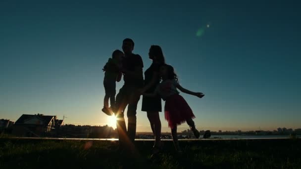 -Apa, anya, lánya és fia kis - boldog család sziluettje a naplemente, lassú mozgás — Stock videók