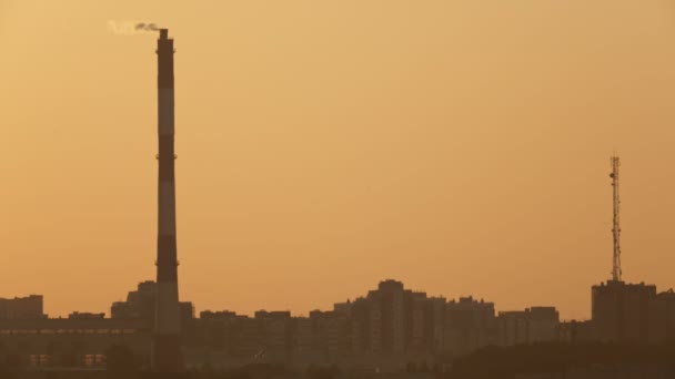 Большие трубы на горизонте города на закате - взгляд на промышленность — стоковое видео