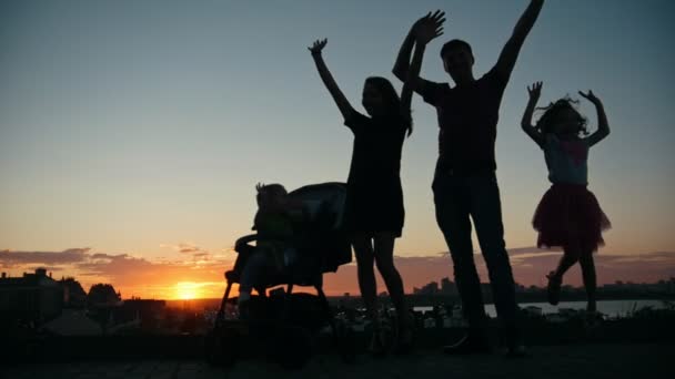 Семья на закате - отец, мать, дочь и маленький сын - силуэт, замедленная съемка — стоковое видео