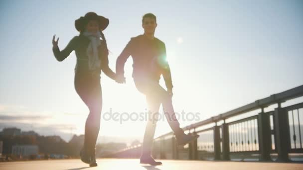 Pareja feliz divirtiéndose al aire libre: hombres y mujeres bailan al atardecer, en cámara lenta — Vídeo de stock