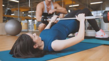 Genç çekici esmer kadınlar egzersiz kalça için-çubuğun üzerinde yatan bir ceset yükselişi