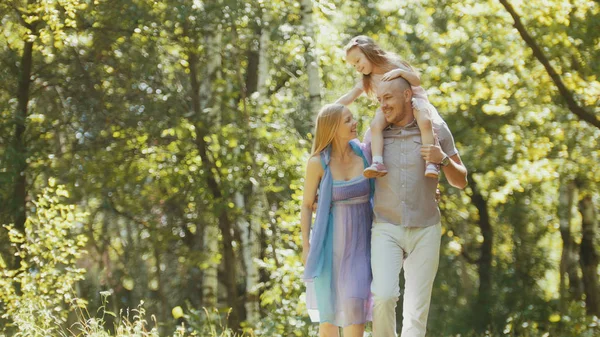 Vader - vet man, moeder - blonde mooie vrouw en een meisje - wandelen in het park op een zonnige dag — Stockfoto