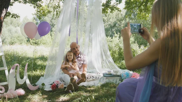 Семейный пикник в парке - мама фотографирует на мобильный телефон — стоковое фото