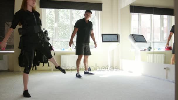 EMS Training - deportistas en el moderno gimnasio usan chaleco de fitness electrónico - entrenador está enseñando para la joven mujer fitness — Vídeo de stock