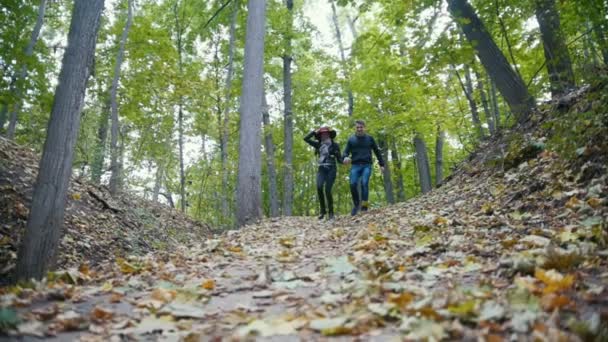 Ungt par på hösten park - ha kul och kör bland gula blad, slow motion — Stockvideo