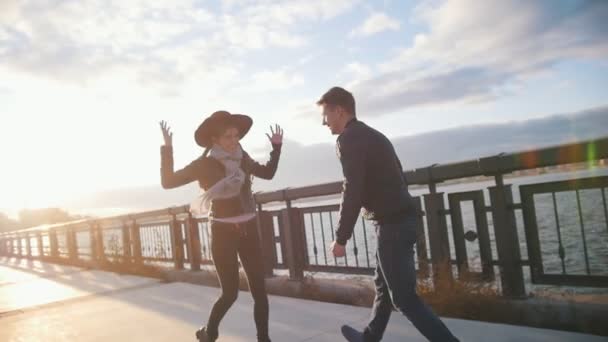 Happy loving para - chłopiec i dziewczynka - zabawę przy promenadzie miasta — Wideo stockowe