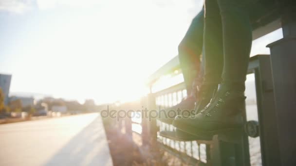 Pareja romántica sentado en el paseo de la ciudad al atardecer y cuelga las piernas — Vídeos de Stock