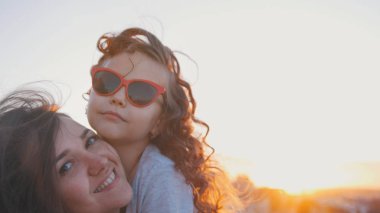 Mutlu anne ve küçük kızı günbatımı üzerinde