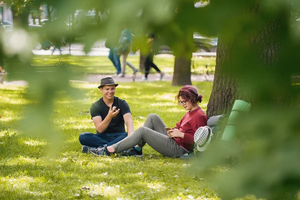 Giovani turisti uomini e donne con zaini si riposano nel parco — Foto Stock