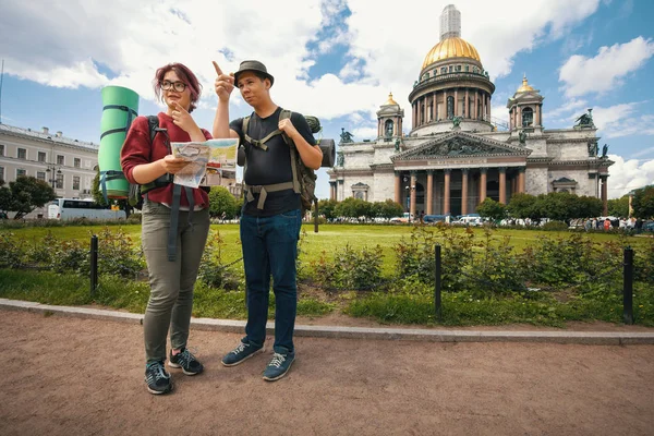 年轻的游客们看纸质地图在俄罗斯圣彼得堡的标志性建筑上的路由 — 图库照片