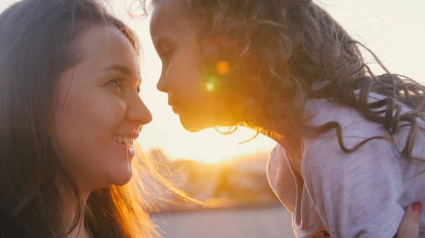 Portret van gelukkige moeder en dochtertje over zonsondergang — Stockfoto