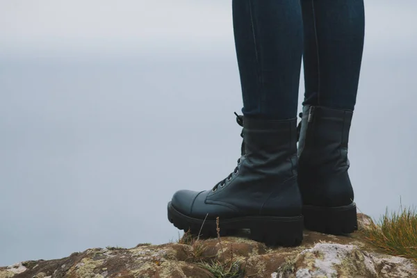 Mulher caminhante pernas em botas grandes no penhasco pico da montanha — Fotografia de Stock