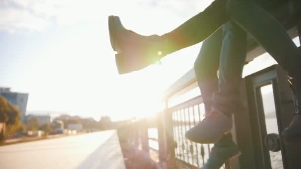 Романтична пара хлопчик і дівчинка сидять на міській набережній на заході сонця — стокове відео