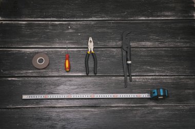 Çalışma araçlar - tornavida, ayarlanabilir anahtarı, pense, koli bandı ve şerit metre ahşap arka plan üzerinde Üstten Görünüm