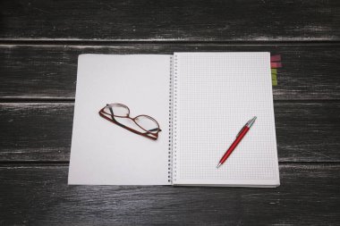 Beyaz defter, kalem ve gözlük siyah ahşap zemin