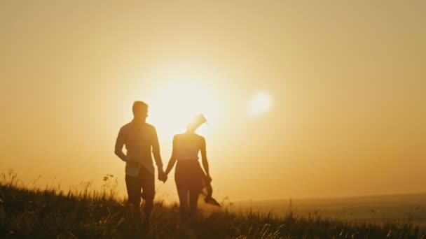 Amor - homem jovem corajoso e menina bonita na silhueta de pôr-do-sol, câmera lenta — Vídeo de Stock