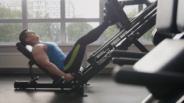 In the gym - muscular man exercising on leg press machine — Stock Photo, Image