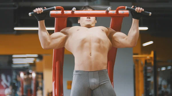 Muscular young man pulling up in a gym, close up — Stock Photo, Image