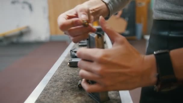 Vrouwtjes handen in schiettent laadt de gun met opsommingstekens — Stockvideo