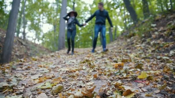 Молодая пара в осеннем парке - веселье и бег среди желтых листьев, замедленная съемка — стоковое видео